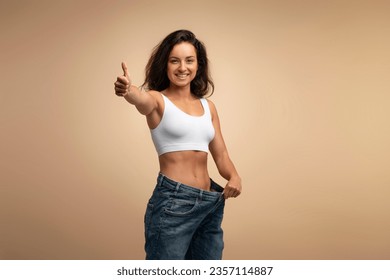 Mulher feliz mostrando calça larga após emagrecer